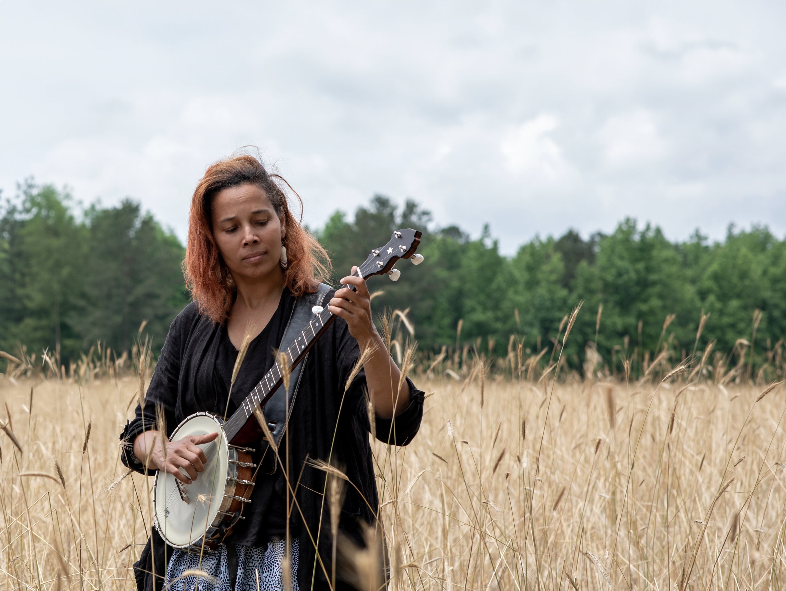 Rhiannon Giddens in a wheat field with banjo