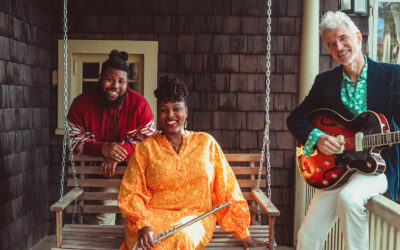 Musicians Dan and Claudia Zanes sitting with Tyree Austin on a front porch swing