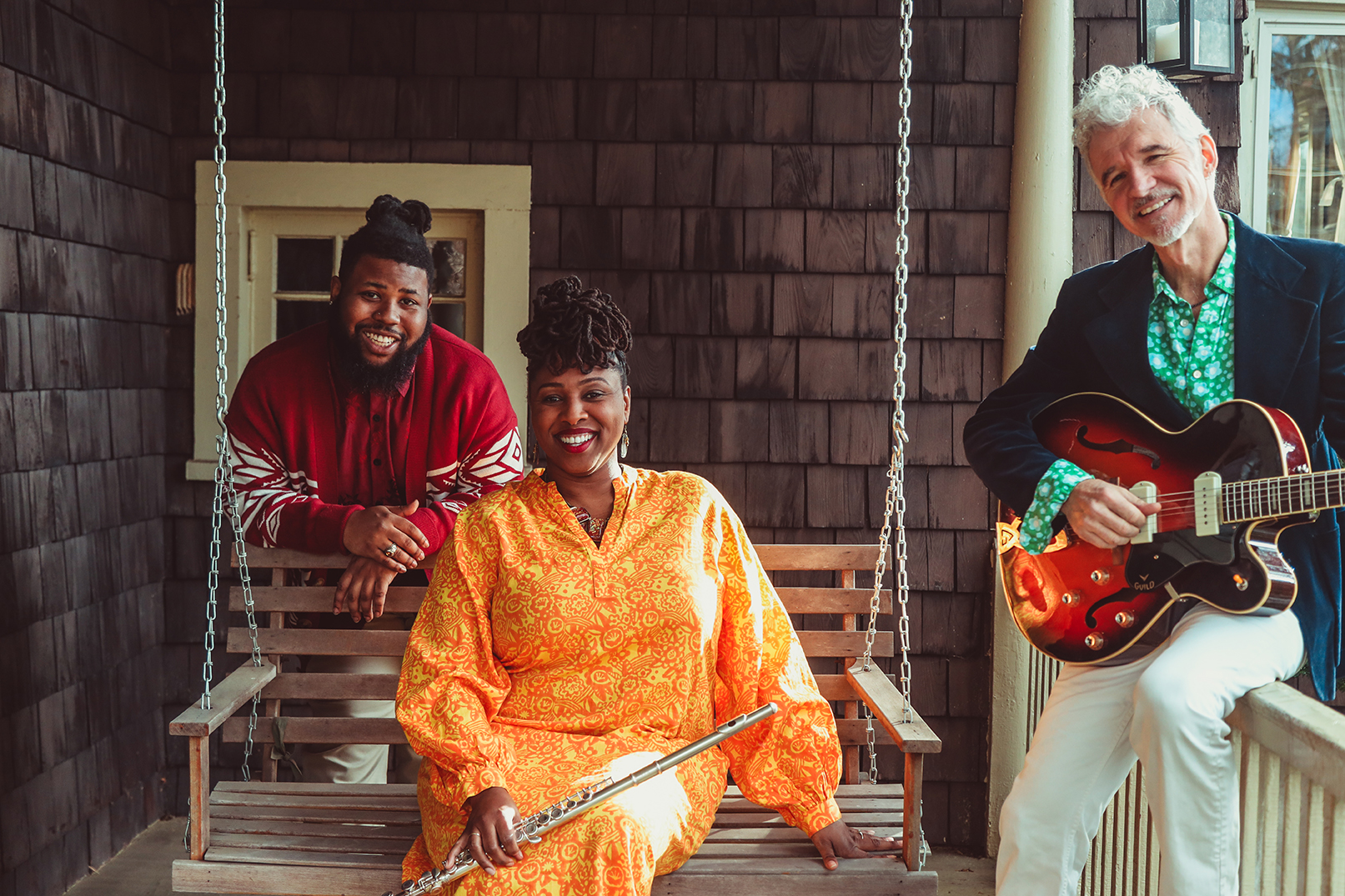 Musicians Dan and Claudia Zanes sitting with Tyree Austin on a front porch swing